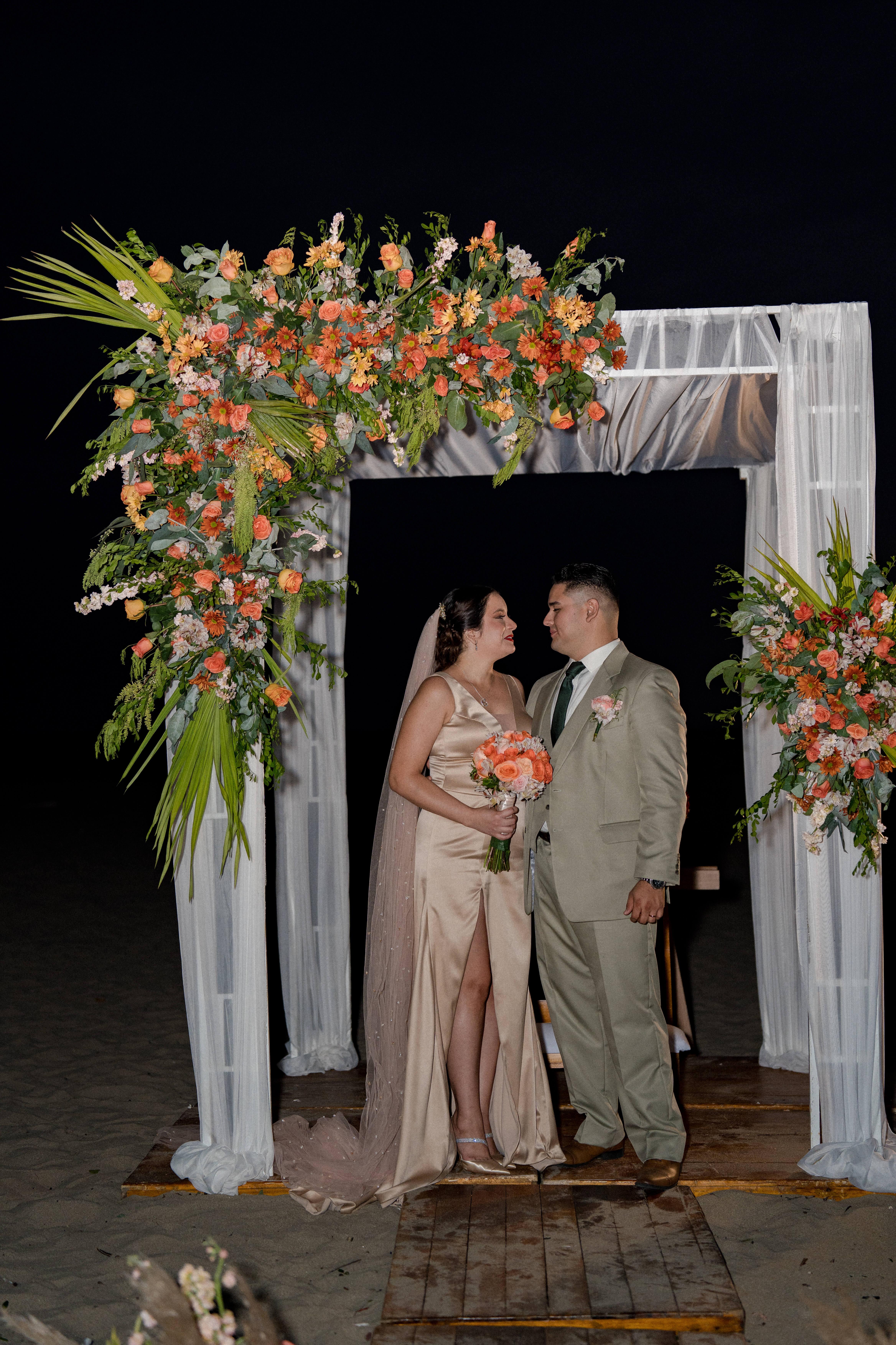 Pareja de novios posando en la playa Playas Ecuador mostrando sus anillos de boda, ramo de rosas rosadas, boda en Chalet Suizo